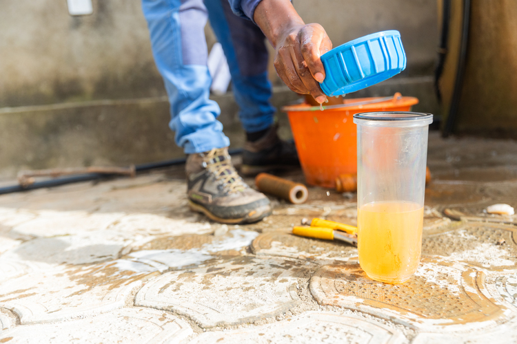 Plumber inspecting discolored contaminated water from a home system