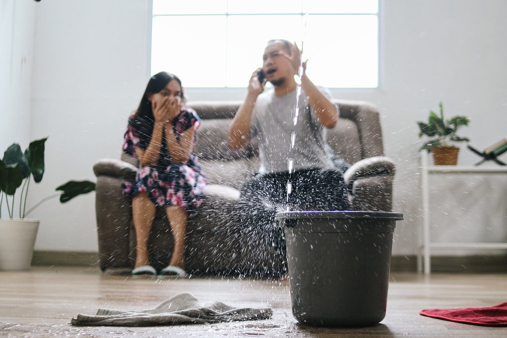 Homeowners responding to a serious roof leak with water entering the living room